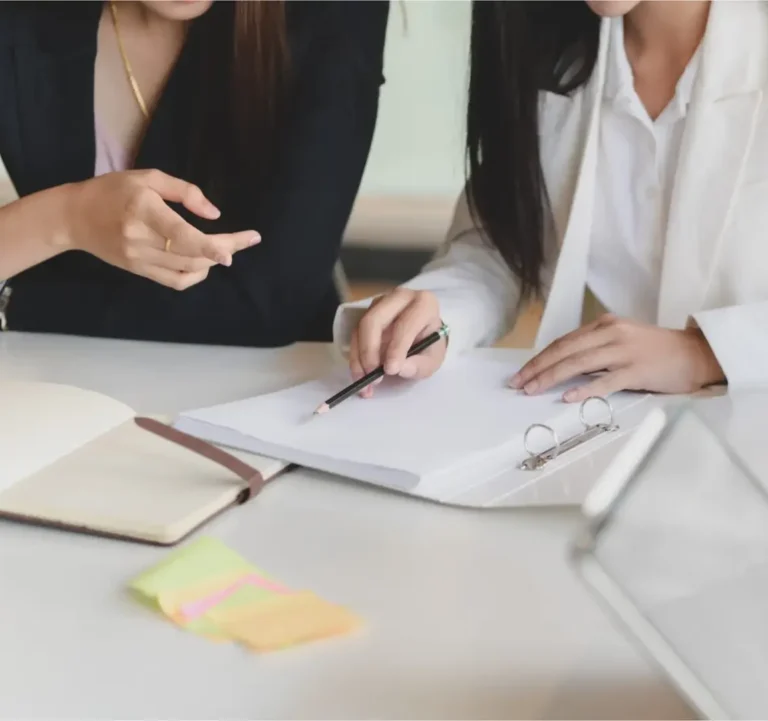 Immobilienexperten prüfen gemeinsam Verkaufsunterlagen und besprechen Dokumente am Konferenztisch.